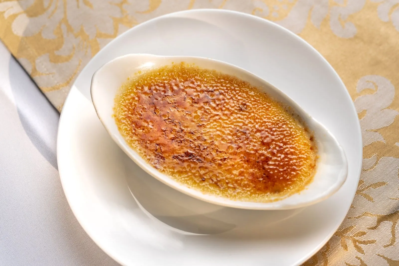 Crème brûlée com a casquinha de açúcar caramelizada servido em ramequim branco