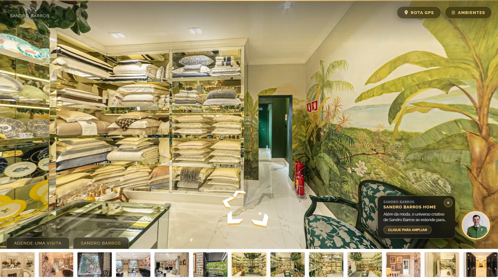 Sandro Barros Home no tour, com estantes de enxoval e louças e um mural tropical, o avatar do Sandro Barros no canto e o balão de prévia Sandro Barros Home com o botão Clique para ampliar