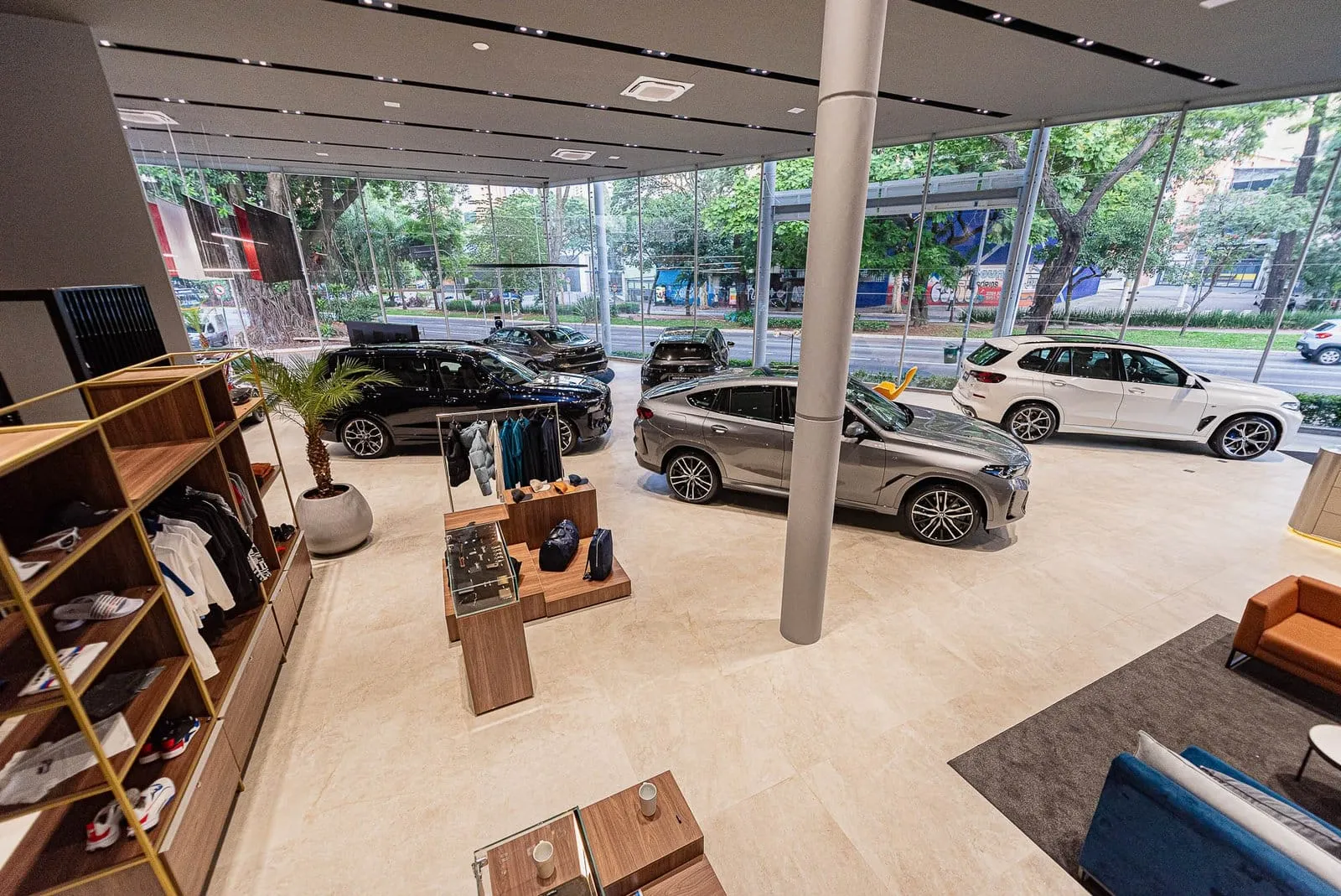 Área de acessórios e lifestyle da BMW Osten Perdizes, com carros BMW expostos ao fundo
