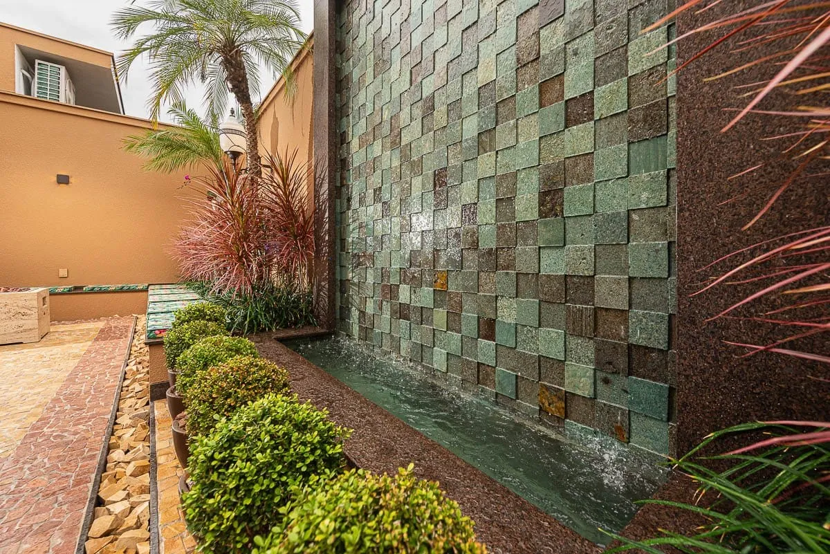 Parede revestida de pedra com jardim ao pé, em imóvel com pedras da Natugran