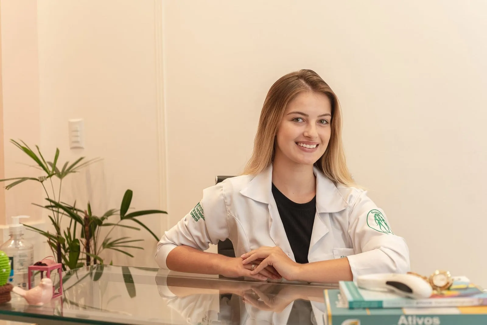 Profissional de jaleco sentada à mesa de atendimento, em retrato com luz suave