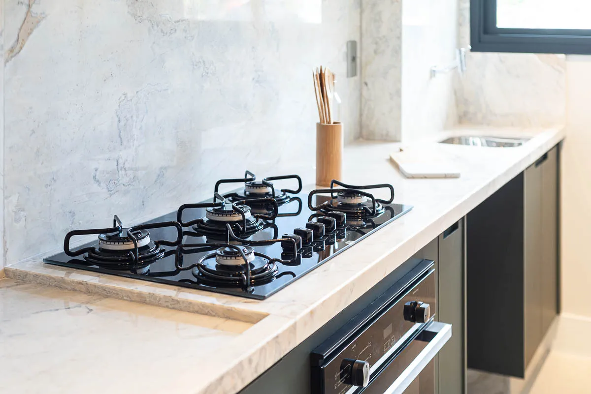 Detalhe do cooktop e bancada de mármore da cozinha do decorado Horizon Vila Rosa