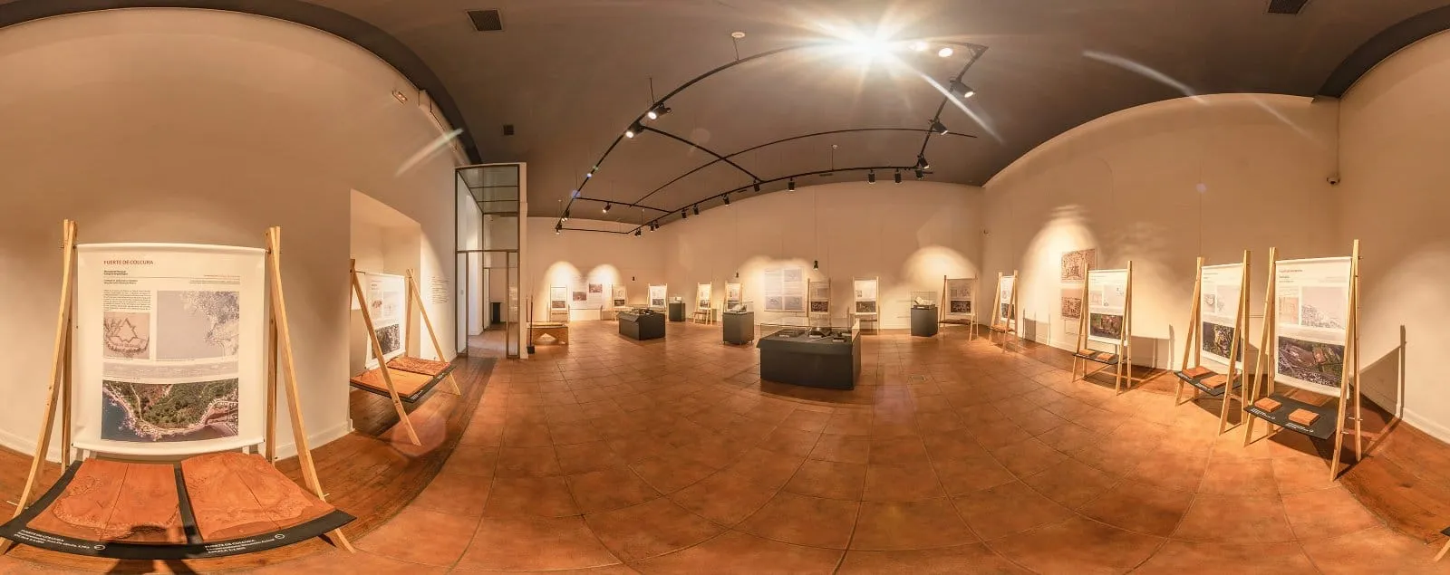 Sala da mostra temporária Fortes Espanhóis, com painéis em cavaletes de madeira, vitrines no centro e trilho de luz no teto