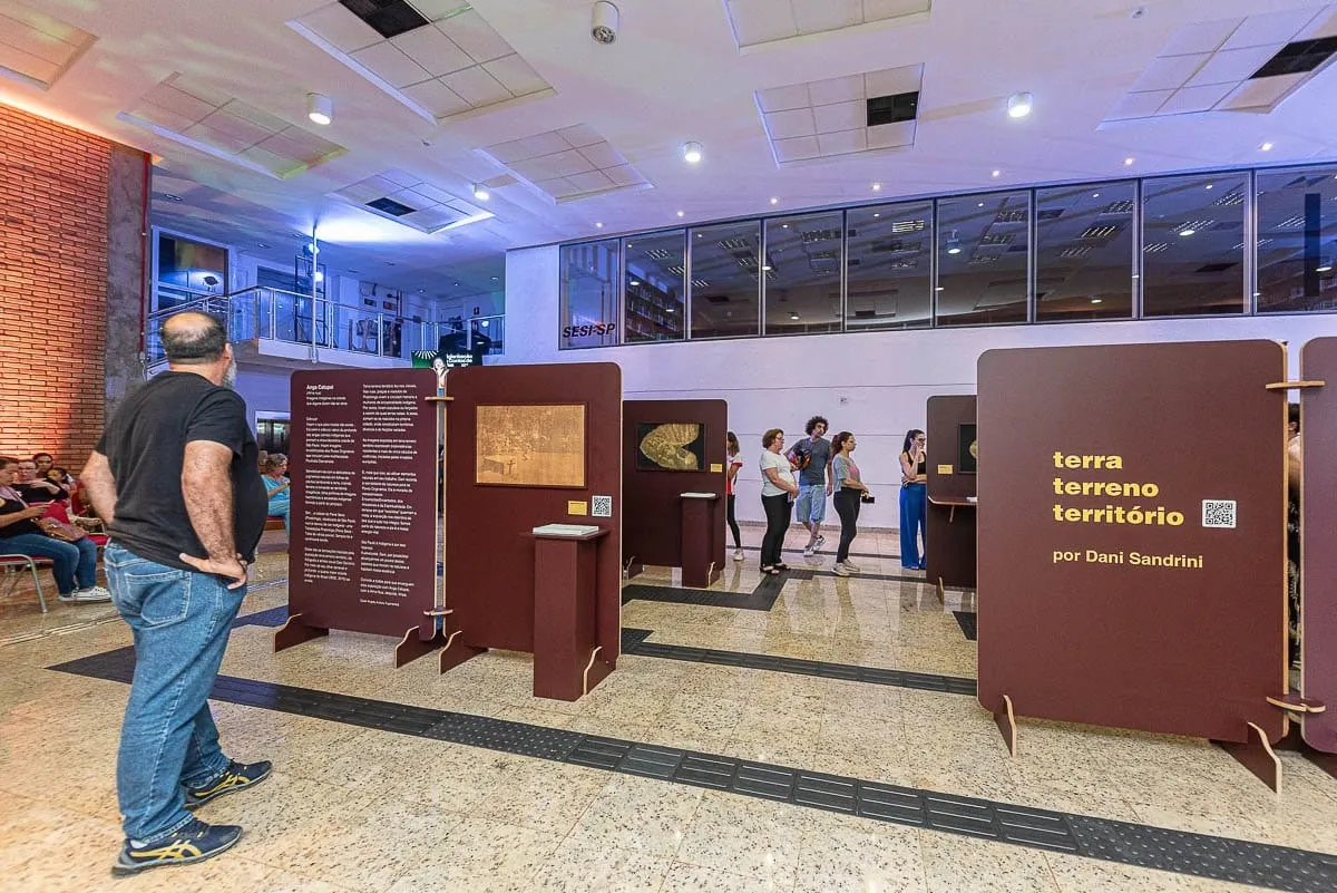 Painéis da exposição Terra Terreno Território montados no saguão, com visitantes