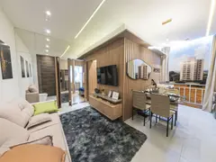 Living do apartamento decorado do Portobelo Residencial: sofá claro, painel ripado de madeira com TV, mesa de jantar de vidro e a Sacada Grill ao fundo