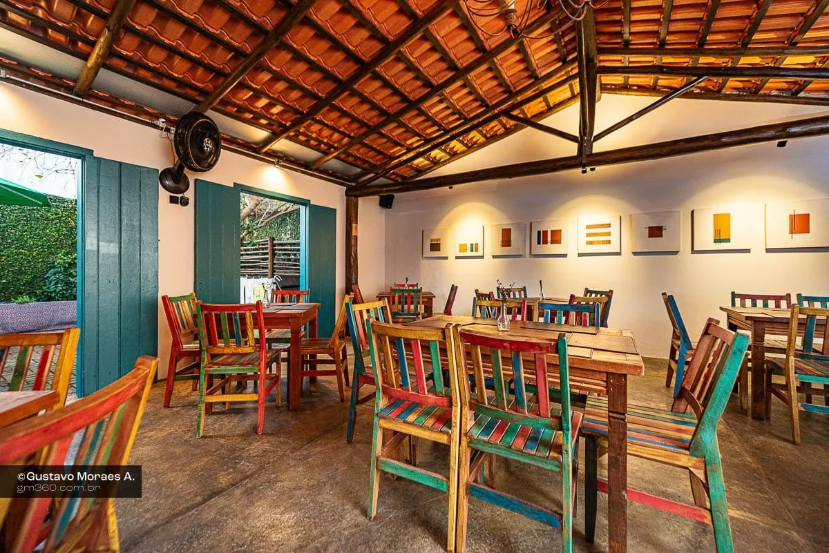 Salão do Quintal Iwasa'i com cadeiras coloridas e quadros nas paredes