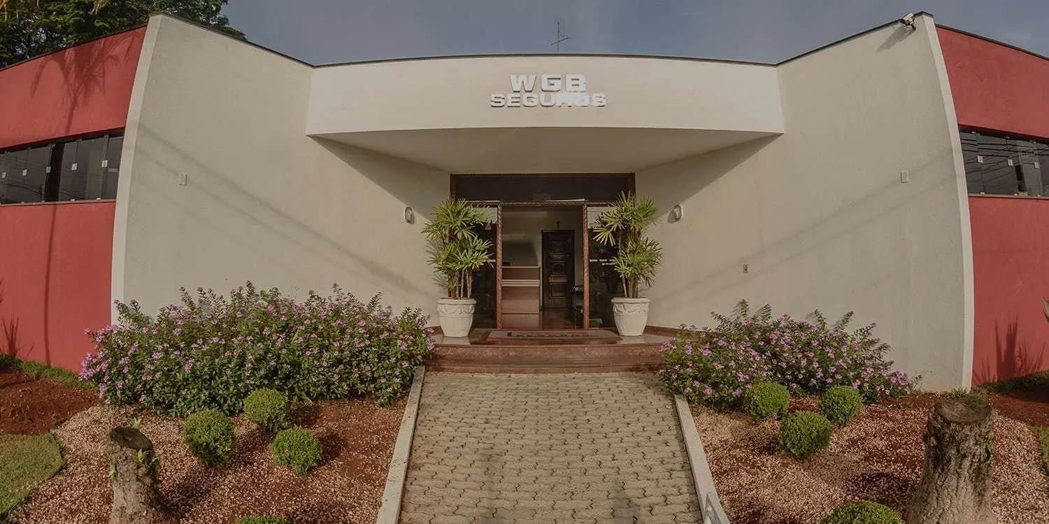 Fachada da WGB Seguros, com entrada central, vasos de plantas e jardim em frente